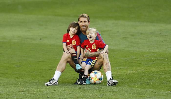Sergio Ramos y sus hijos con la camiseta de la selección española sentados en el pasto.